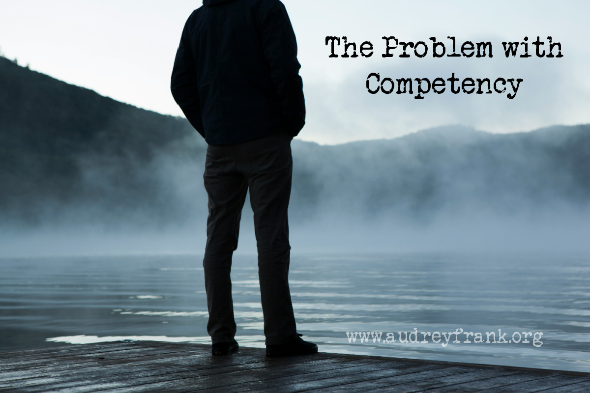 A person standing overlooking a lake with the words "The Problem with Competency" describing the subject of the post.