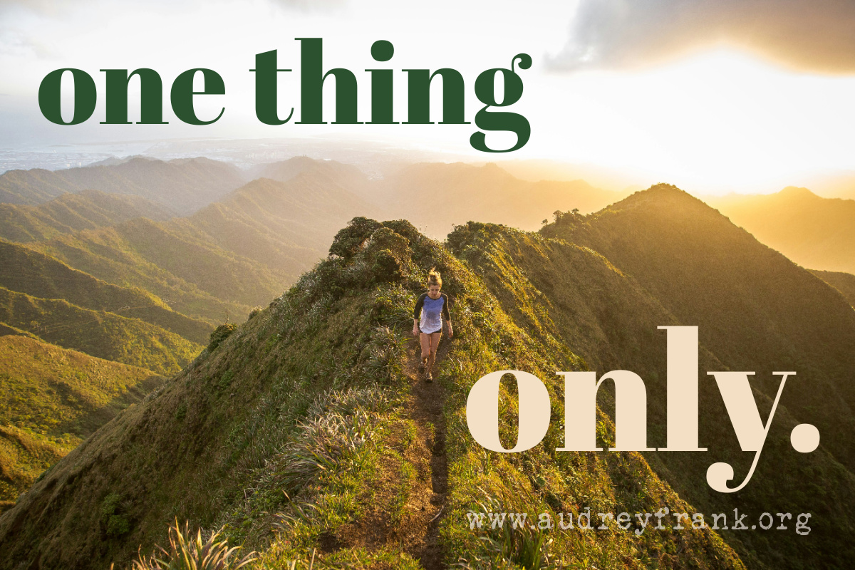 A woman running along a narrow path crossing mountain peaks, with the words, "One Thing Only" describing the subject of the post.